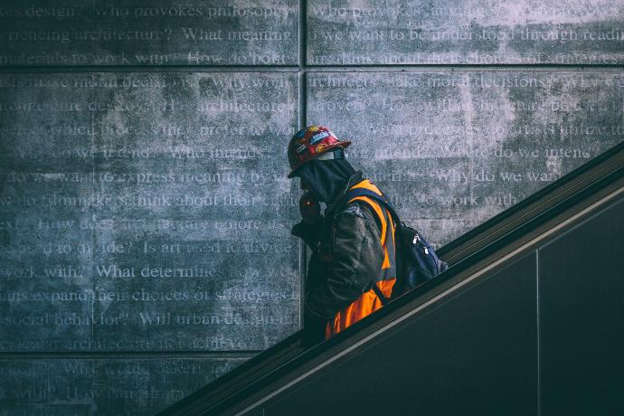 a man wearing a hard hat and safety gear walking down an escalator